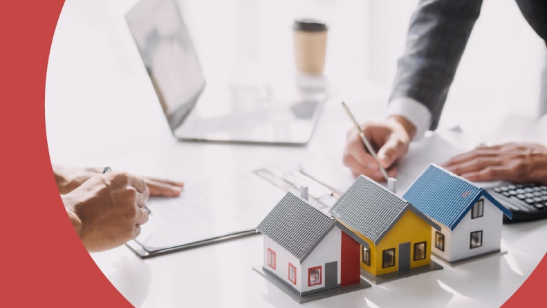 A real estate brokerage agent and a customer with model houses and a mortgage loan agreement.