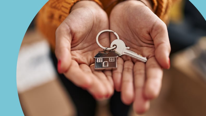 A woman's hands holding a key with a house keychain.