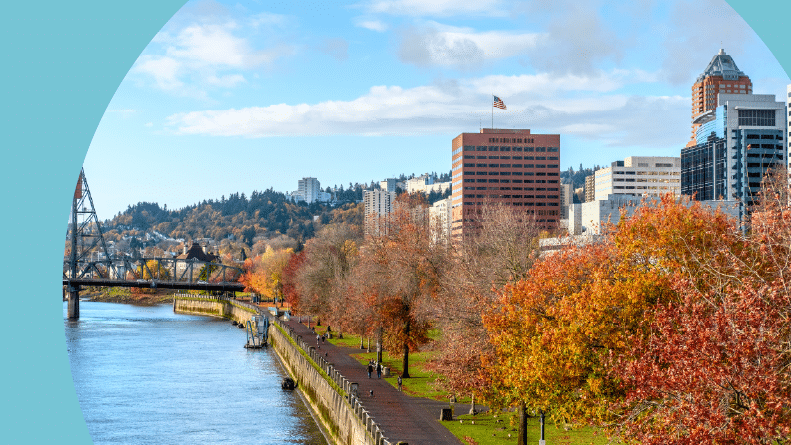 A walkway along the water beside the Portland, Oregon city skyline in autumn.
