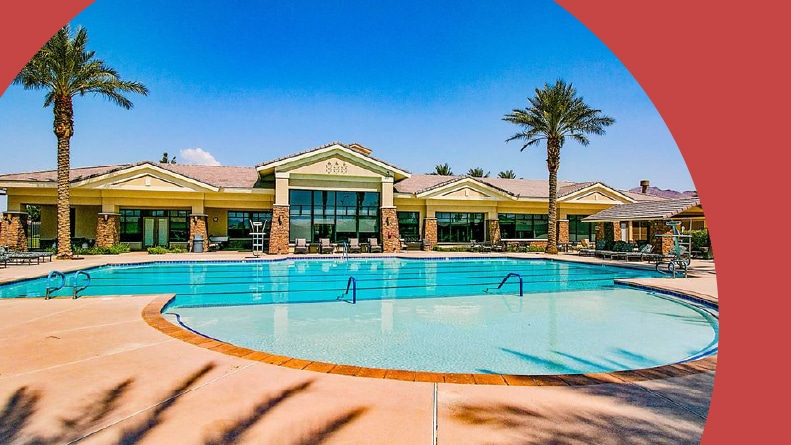 Palm trees and lounge chairs beside the outdoor pool and clubhouse at Solera at Stallion Mountain in Las Vegas, Nevada.