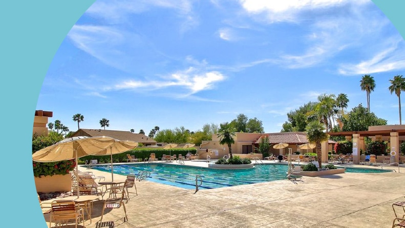 Palm trees and lounge chairs beside the outdoor pool at Westbrook Village in Peoria, Arizona.