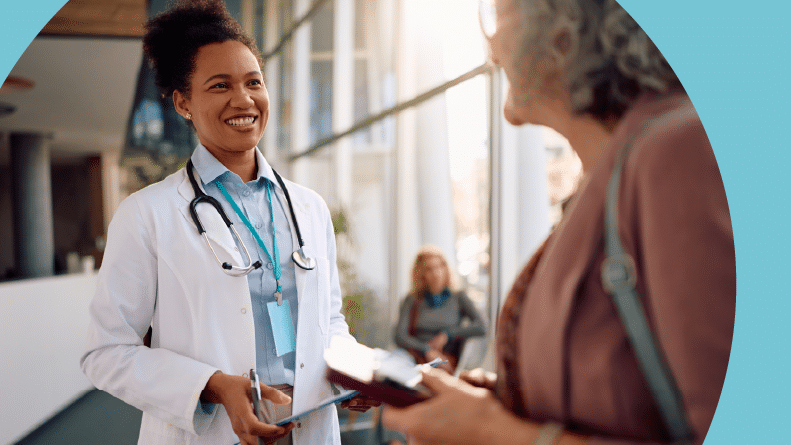 A doctor and her 55+ patient communicating during a medical appointment at a clinic.