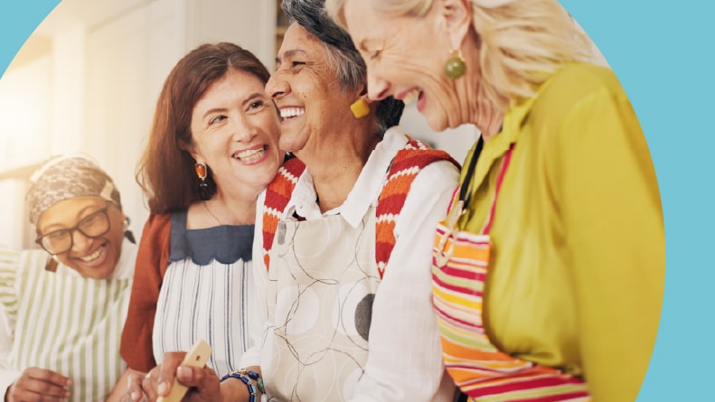 A group of 55+ women cooking and laughing together.