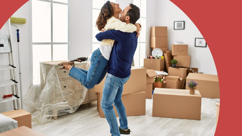 A happy 55+ couple hugging in their new home.