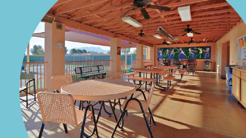 Tables and chairs on a patio beside tennis courts at Green Valley Recreation in Green Valley, Arizona.