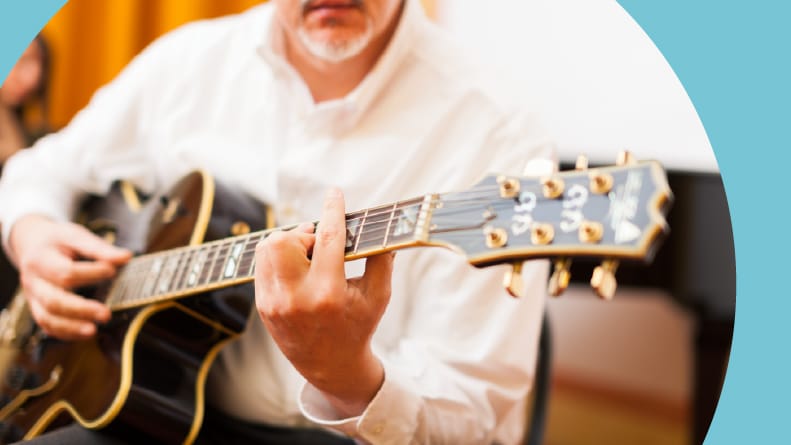 A 55+ musician playing an archtop guitar.