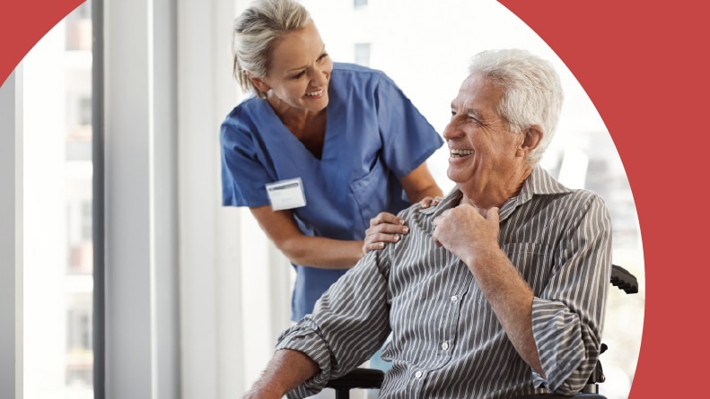 A nurse smiling at a patient in a wheelchair.