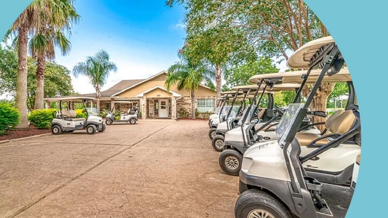 Golf carts on a palm tree lined roadway in front of the clubhouse at CountryPlace in Pearland, TX.