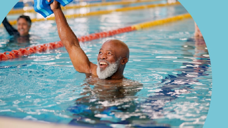 A 55+ man enjoying a water aerobics class.