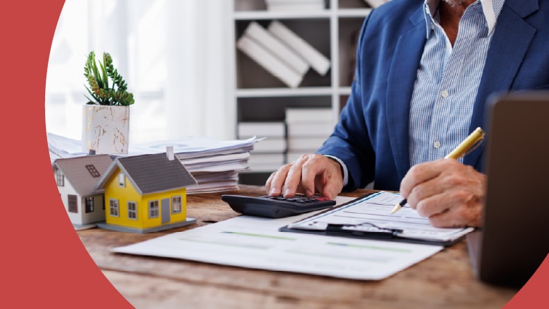 A 55+ man at a desk with paperwork and a calculator working on estate taxes.