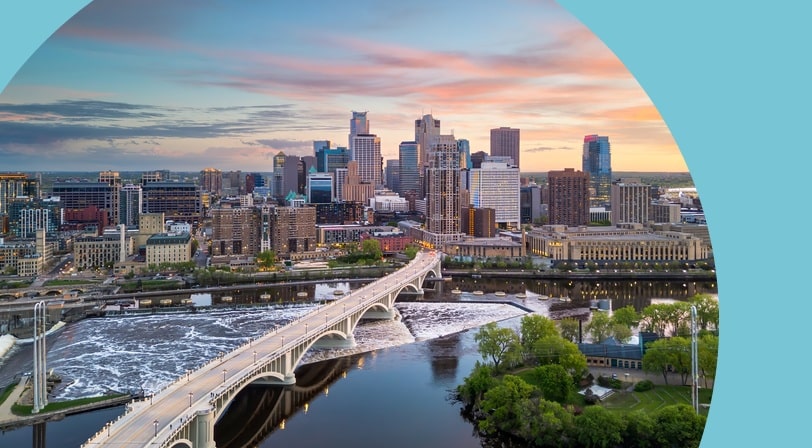 The downtown city skyline in Minneapolis, Minnesota beside the river at dusk.