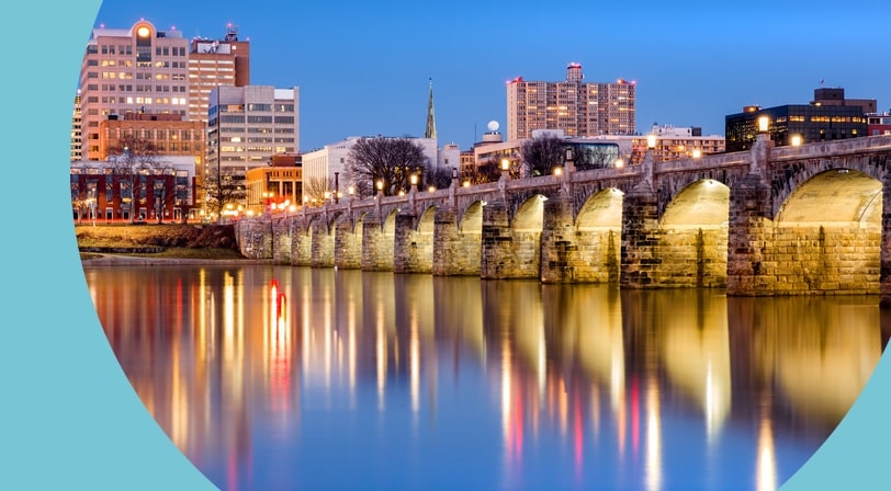 The Harrisburg, Pennsylvania skyline with the historic Market Street Bridge reflected on the Susquehanna River at dusk.