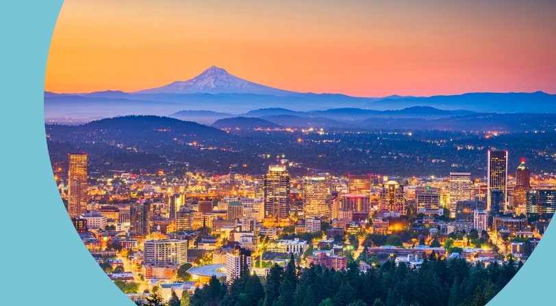 Aerial view of the Portland, Oregon skyline at dusk with Mt. Hood in the distance.