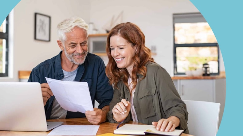 A 55+ man and a younger woman looking at a laptop and papers.
