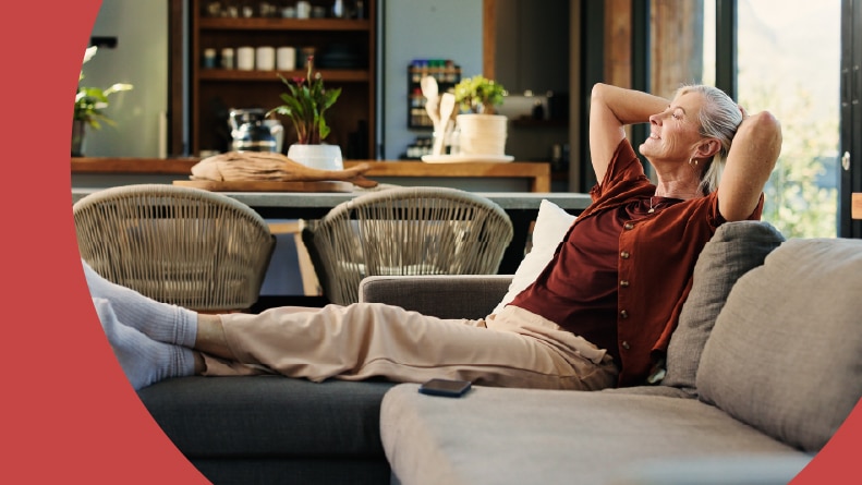 A happy woman relaxing on a couch in her apartment.