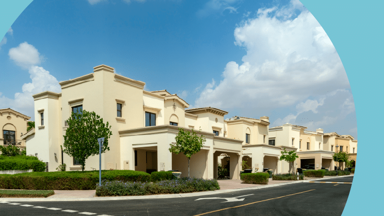 Villas lining a residential street on a bright sunny day with white clouds in the blu sky.