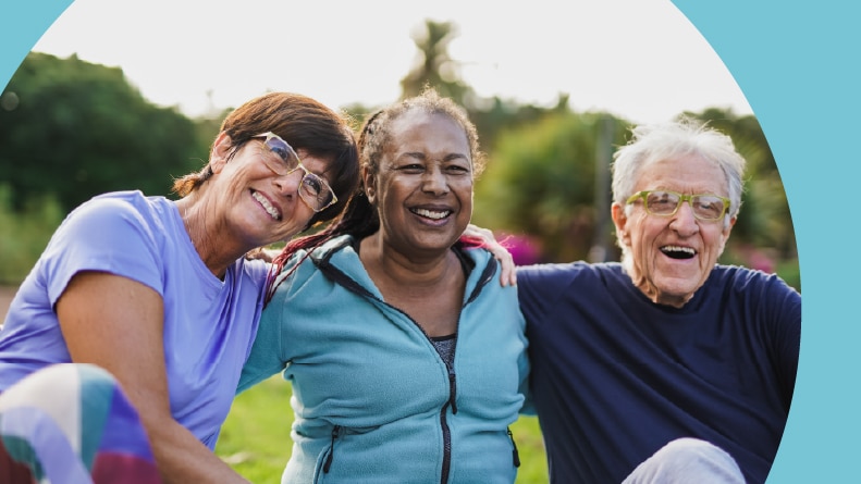 Happy active adults hugging each other after an outdoor yoga lesson in their 55+ community.