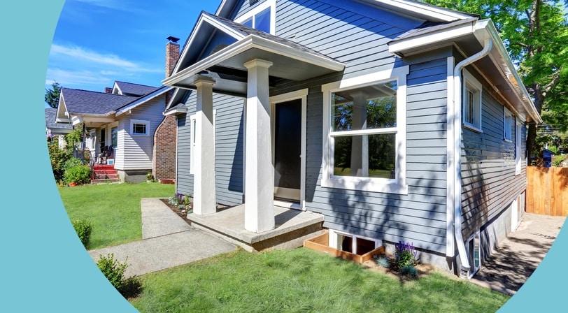 Gray craftsman-style home with a columned entry porch, large front window, and manicured lawn.