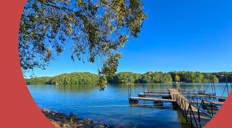 A dock at Lake Lanier Olympic Park surrounded by lush green trees, plants, and grass in Gainesville, Georgia.
