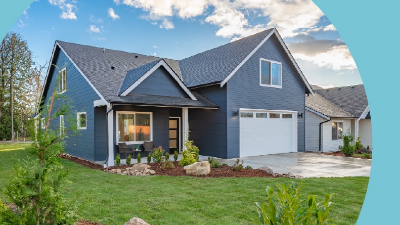 A newly built navy blue craftsman-style home with a white two-car garage, covered front porch, and freshly landscaped lawn.