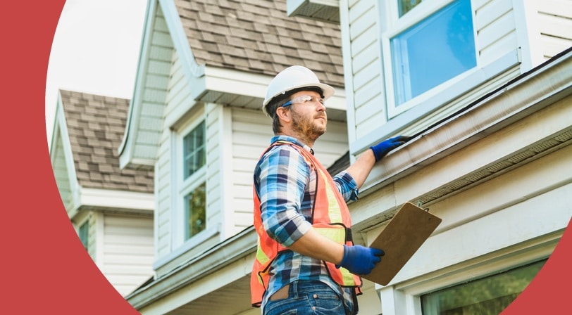 A home inspector examines the roofline and gutters of a house in a 55+ community.