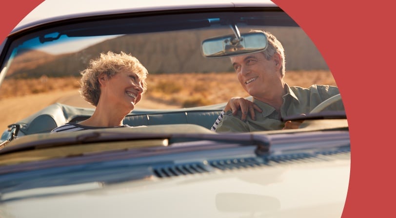 A 55+ couple driving in a convertible through the Arizona desert.