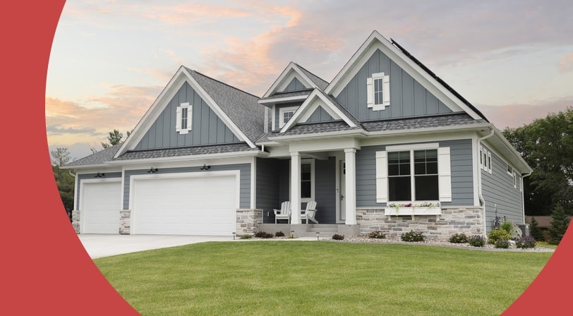 A gray home with white trim, multiple gables, and a three-car garage, photographed at sunset with a colorful sky.