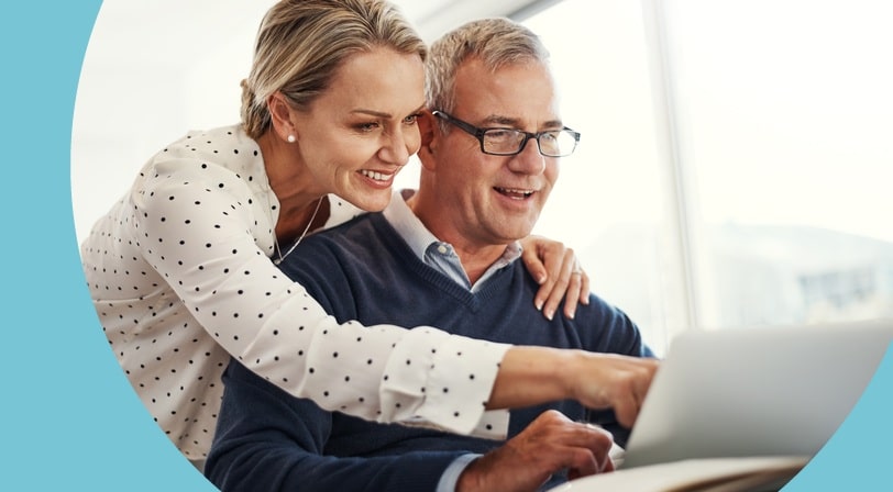 A smiling mature couple reviewing information together on a laptop as they plan their next chapter.