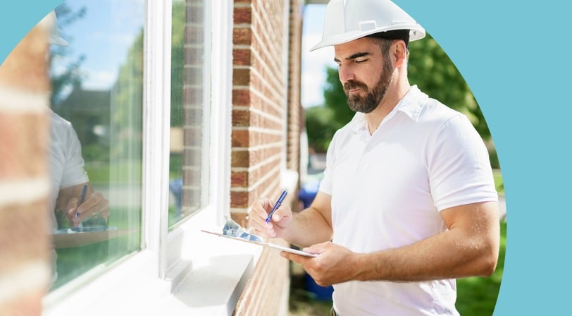 A home inspector reviews notes on a clipboard while checking a window at a 55+ community property.