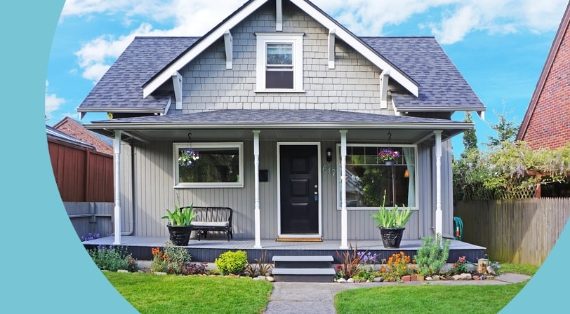A gray craftsman home with white trim, a covered porch, and a landscaped front yard.