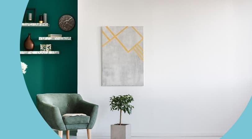 A modern sitting area with a green accent wall, armchair, and potted plant.