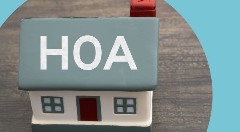 A small model house labeled "HOA" on its roof, sitting on a wood surface.