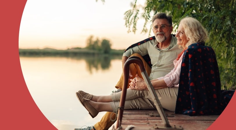 A 55+ couple sit on a dock near their home in one of the cheapest states to retire in.