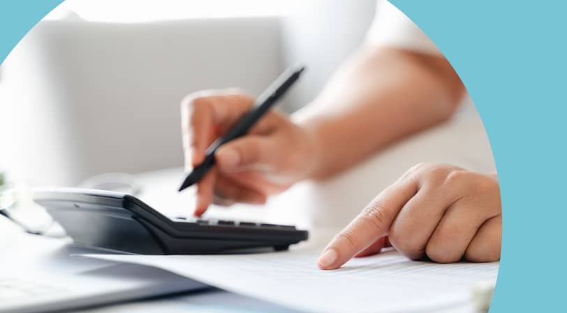 Close-up of hands using a calculator and pen while reviewing a printed document.