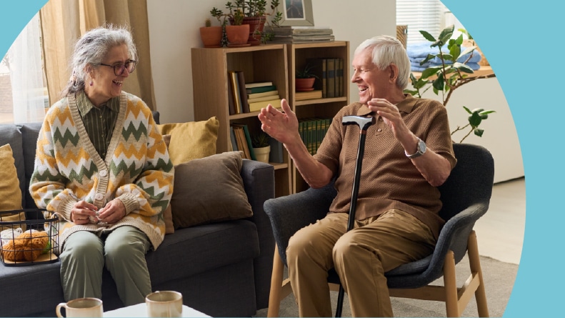 A 55+ couple smiling and laughing together at home.
