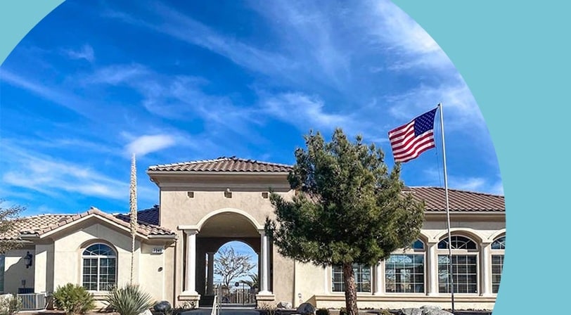 Community entrance archway with American flag at Desert Vista Village, a 55+ community in Yucca Valley, California.