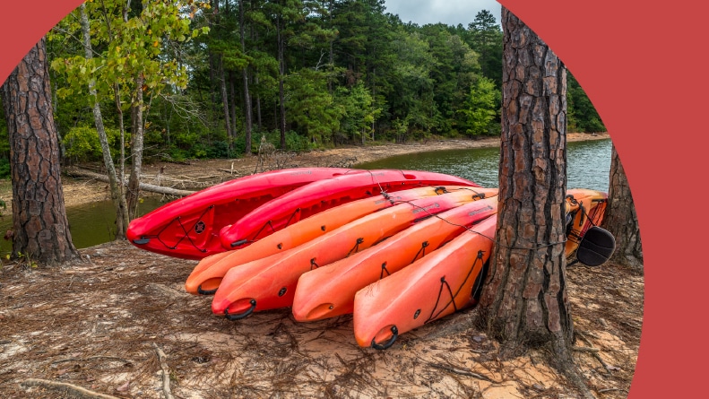 Several kayaks tied together on the beach against a tree at the lake in Gainesville, Georgia.
