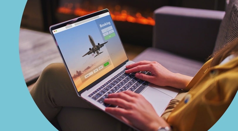 Computer open on person's lap with the screen showing an airline booking site.