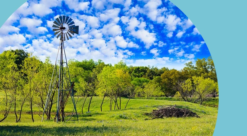 A windmill in a field in Texas on a sunny day.