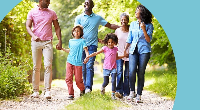 A multigenerational family walking together along a tree-lined path.
