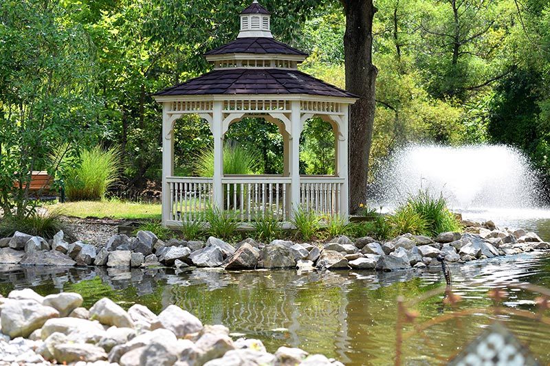 A gazebo, water fountain, trees, rocks, and a lake at Prophecy Creek Park in Ambler, Pennsylvania.