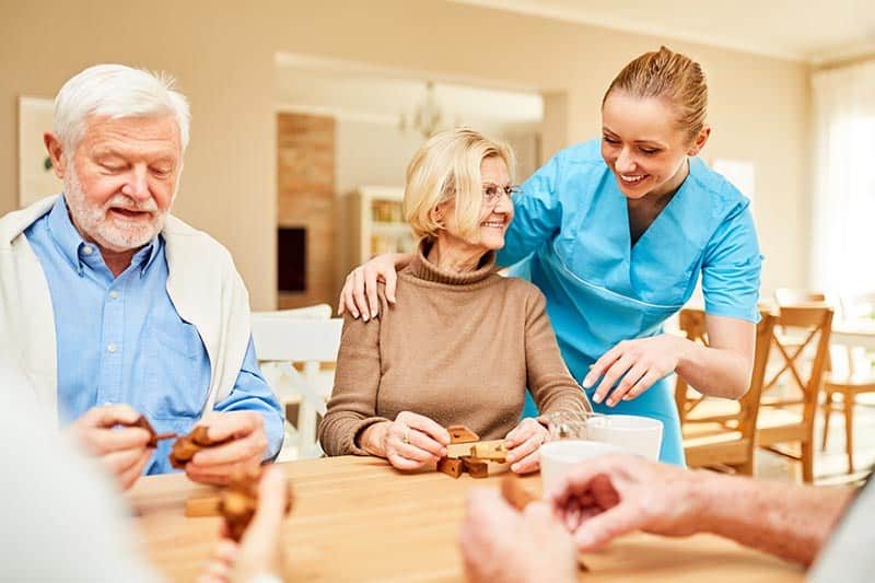 A caregiver cares for senior citizens with patience.