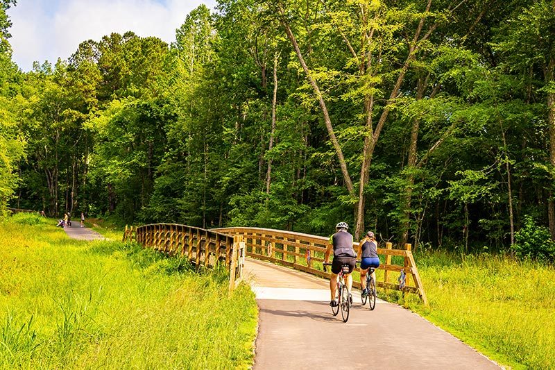 A couple riding bikes on the Clayton River Walk Greenway in Clayton, North Carolina.