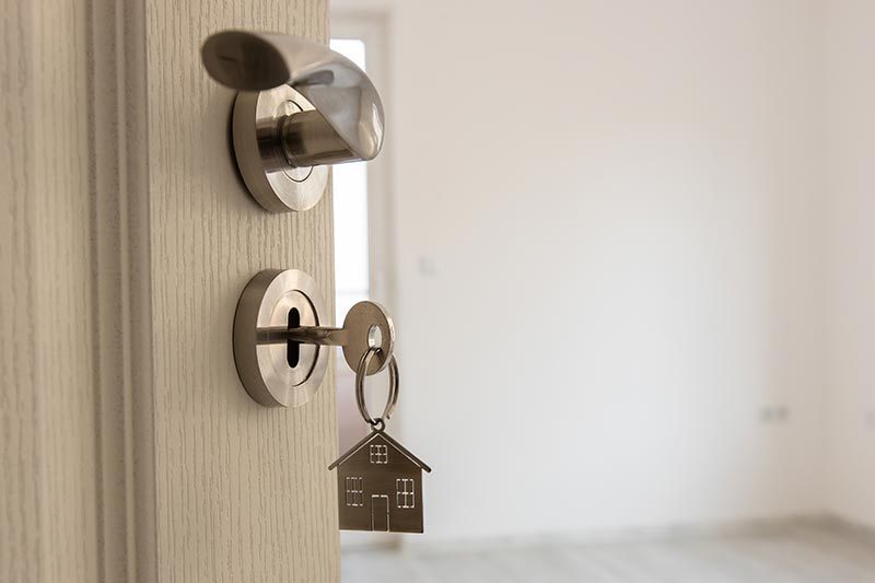 A door to a new home with a key in the lock with a house keychain.