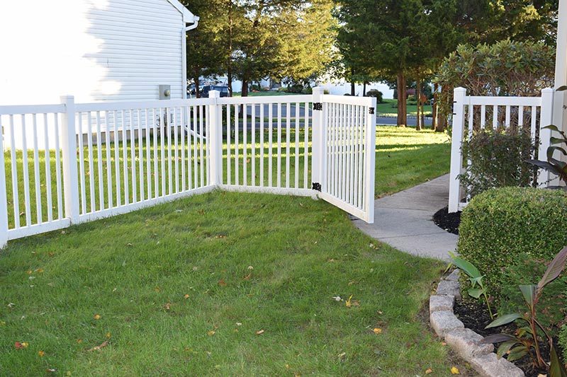 A white fence with a gate surrounding the yard of a house in a 55+ community.