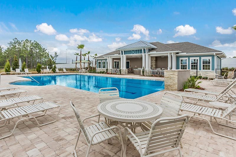 Tables and lounge chairs beside the outdoor pool at Freedom at Arbor Mill in Jacksonville, Florida.