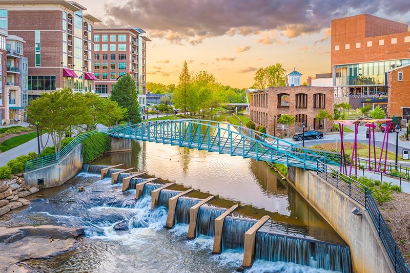 The downtown cityscape of Greenville, South Carolina on the Reedy River at dusk.