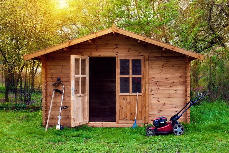 Lawn tools sitting outside of a wooden shed in a 55+ community.