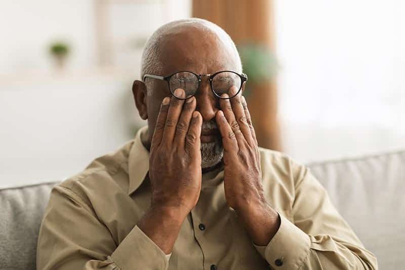 A senior man rubbing tired eyes.