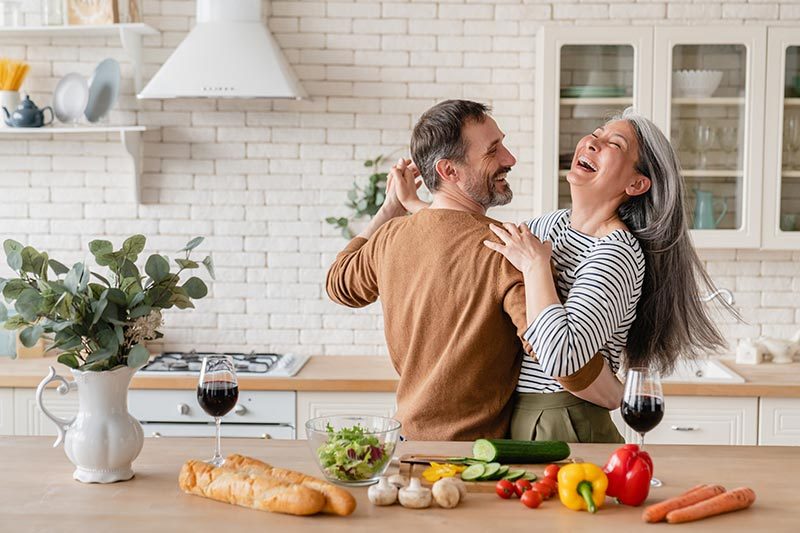 Cheerful mature couple dancing together in the kitchen and cooking